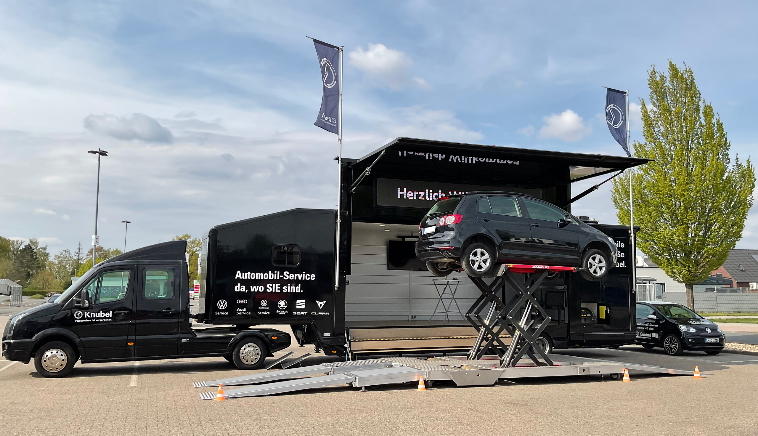 Das Knubel Service mobil mit ausgefahrener Hebeb&uuml;hne und einem Auto darauf.